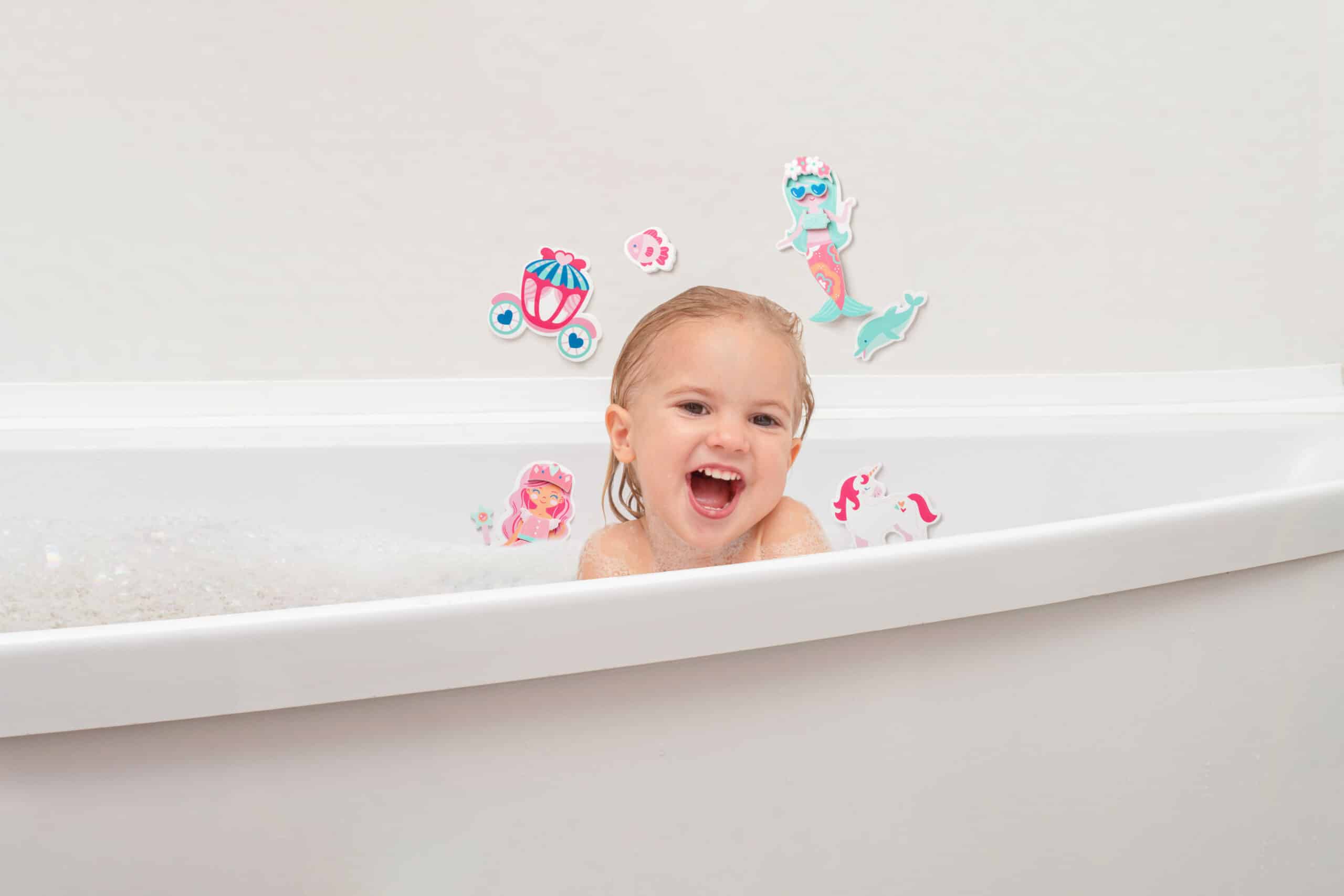 Cute kid plays with white foam at bathroom, laughts and smiling, happy childhood
